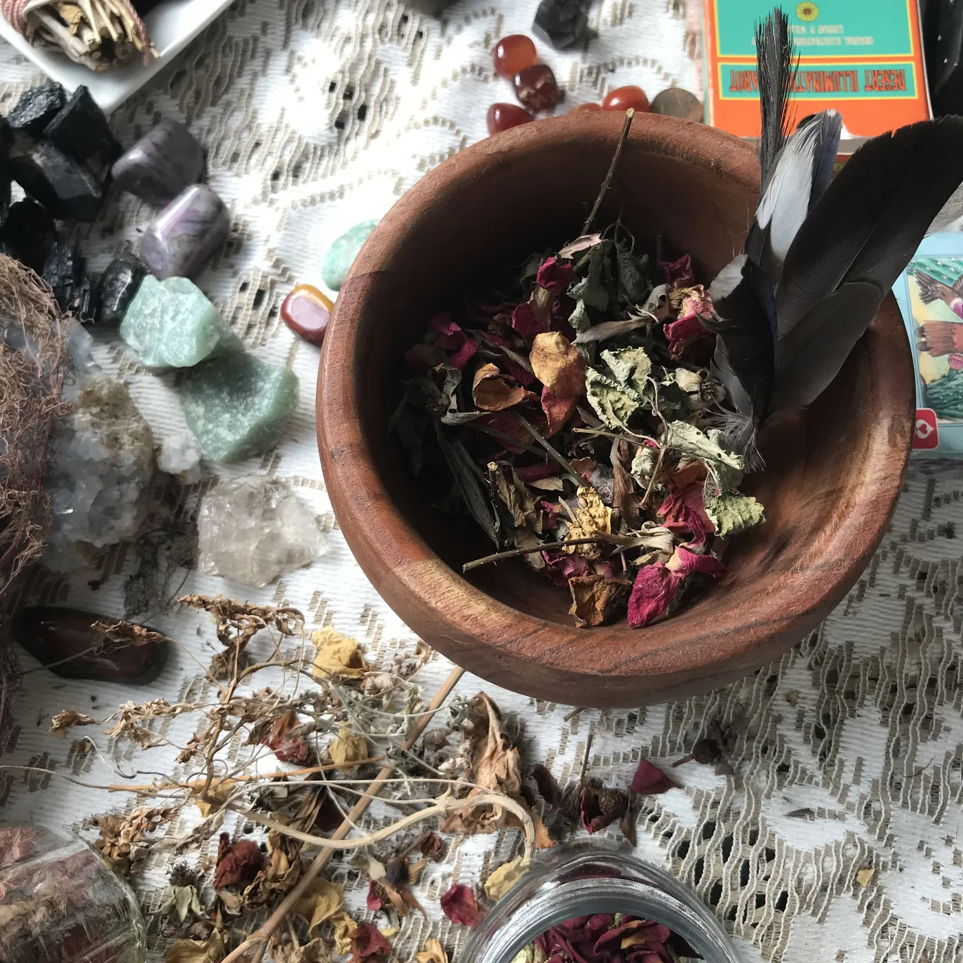 Jamie's reading table with crystals, dried botanicals, a feather bowl, and a tarot deck