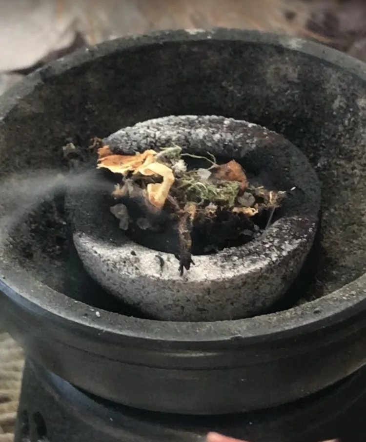 A zodiac burn smoking on a charcoal disc in a stone burner
